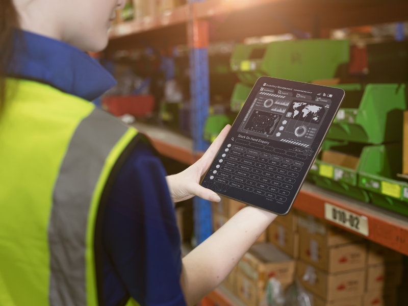 Worker in warehouse checking stock levels on a digital tablet