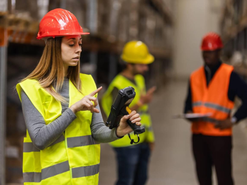 Warehouse workers in safety vests scanning managed inventory with barcode devices
