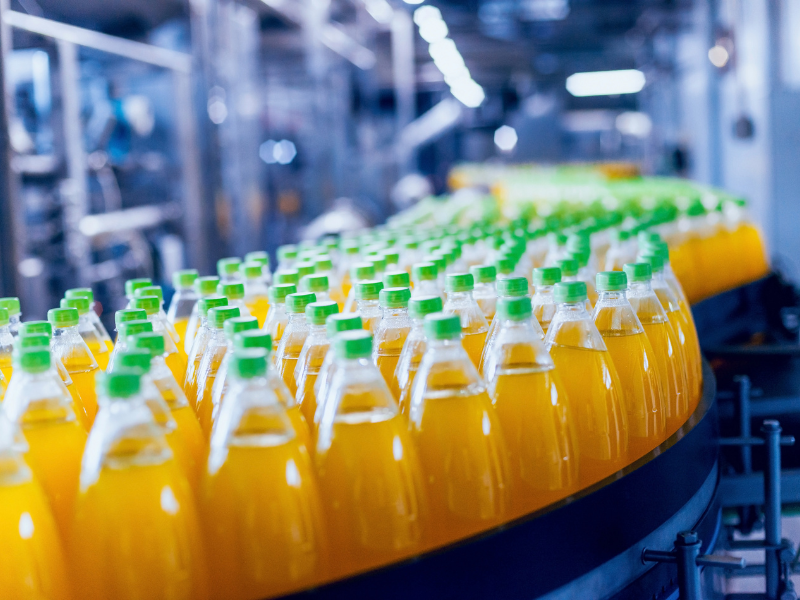 Bottled orange juice lined up in a warehousing production facility