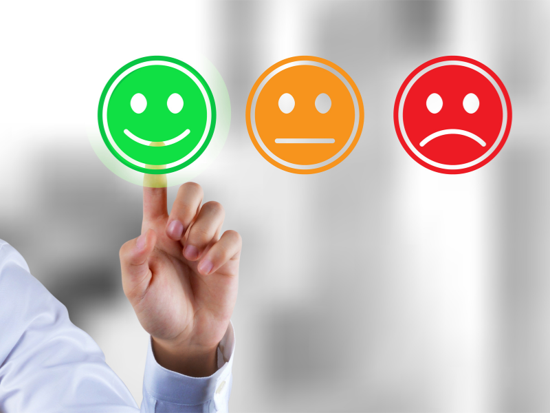 Hand selecting a green happy face for customer satisfaction feedback