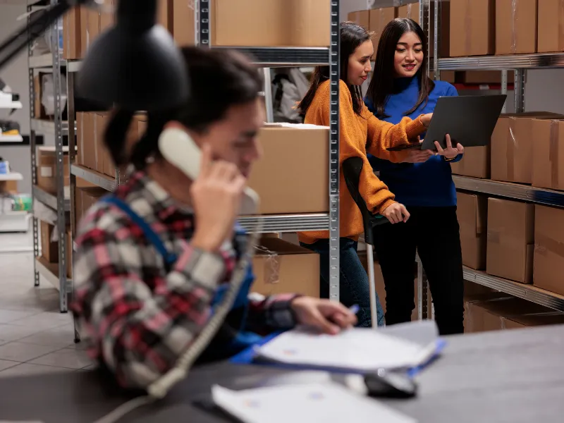 Employees discussing vendor managed inventory strategies in storage facility