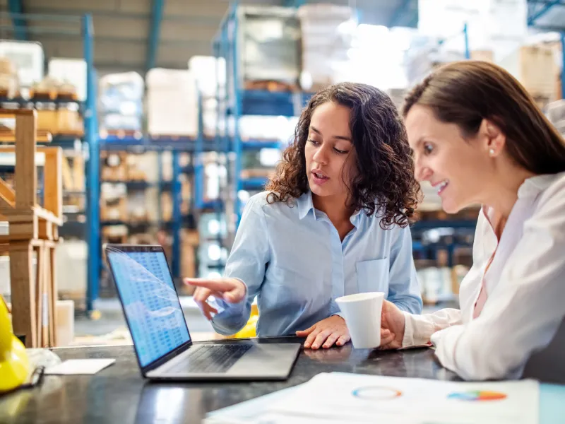 Two women analyzing vendor management inventory data in warehouse setting