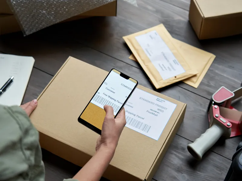Smartphone scans shipping label for streamlined fulfillment tracking and package delivery confirmation
