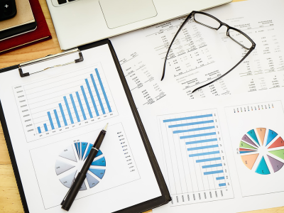 Various charts and graphs show managed inventory trends and stock level comparisons on a desk