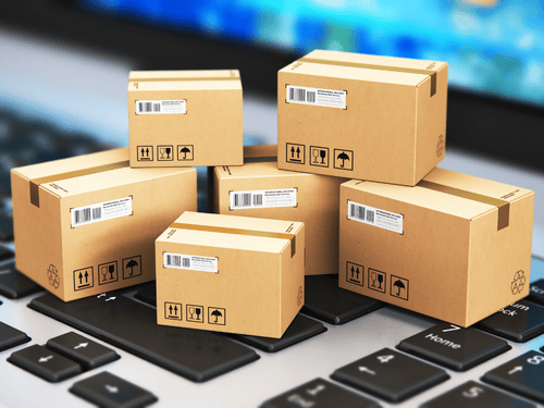 Multiple cardboard boxes are stacked on a keyboard, representing e-commerce fulfillment and carrier integration