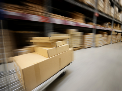 Blurred motion image of packages on a cart, showing quick 3PL warehouse order processing