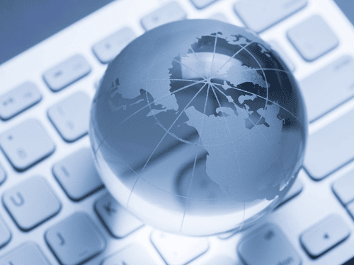 A glass globe rests on a keyboard, symbolizing global delivery systems and international carrier logistics