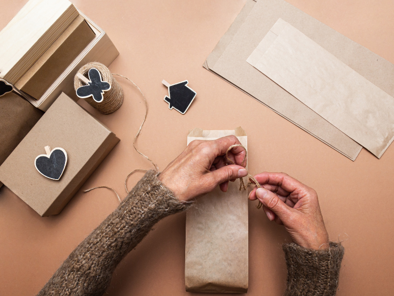 A person ties twine around eco-friendly packaging using simple materials and decorative tags