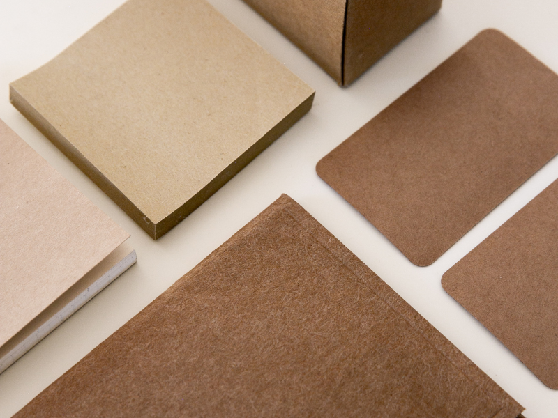 A flat lay of recycled brown paper packaging materials including boxes, cards, and notebooks