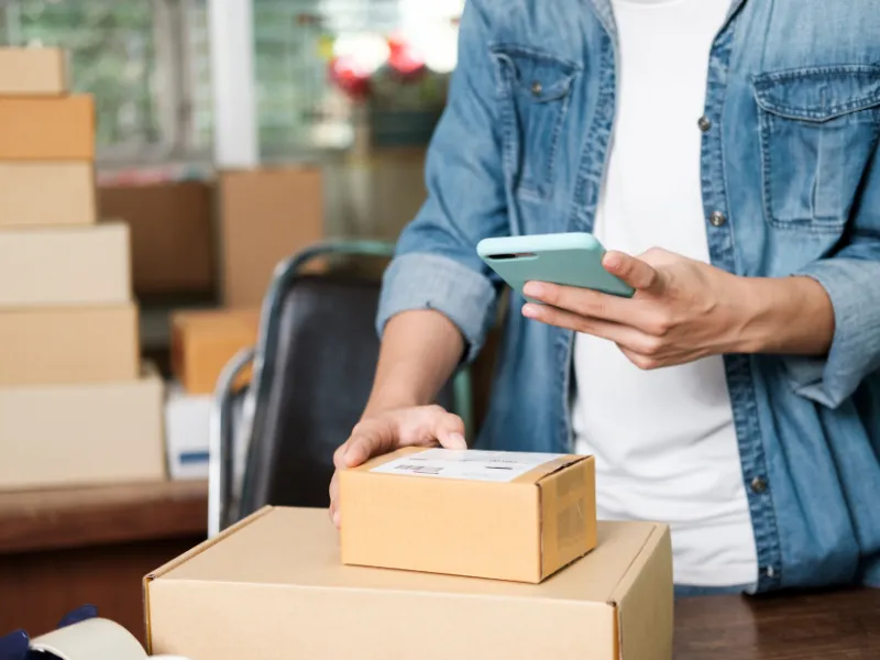Person uses phone to manage product shipping and fulfillment in small business environment