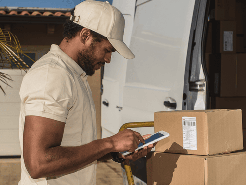 A delivery driver scans a package, highlighting tracking-related carrier mistakes that cause shipment errors