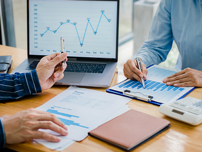 Business professionals discuss managed inventory performance using data charts and a laptop screen