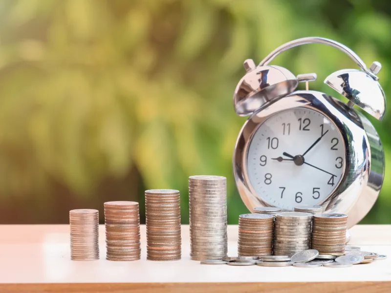 Coin stacks and clock representing time and money savings through efficient warehousing practices