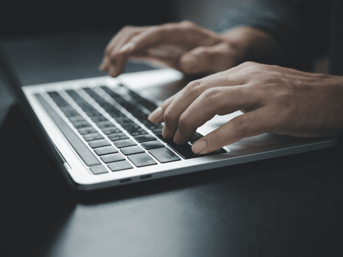 Person types on laptop using tech tools to streamline business operations and logistics planning